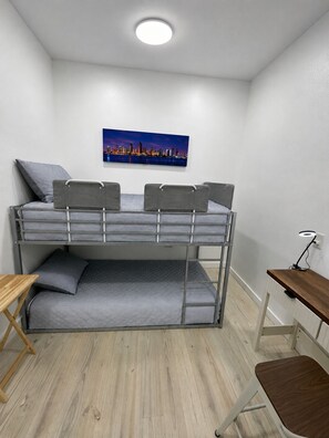A bunk bed with a desk and chair, a small table, and a cityscape painting on the wall. - Marvelous 3-bedroom townhome with AC in Port Aransas (Port Aransas)
