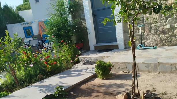 Ett barn leker i en liten uppblåsbar pool, med ett hus och en trädgård i bakgrunden.