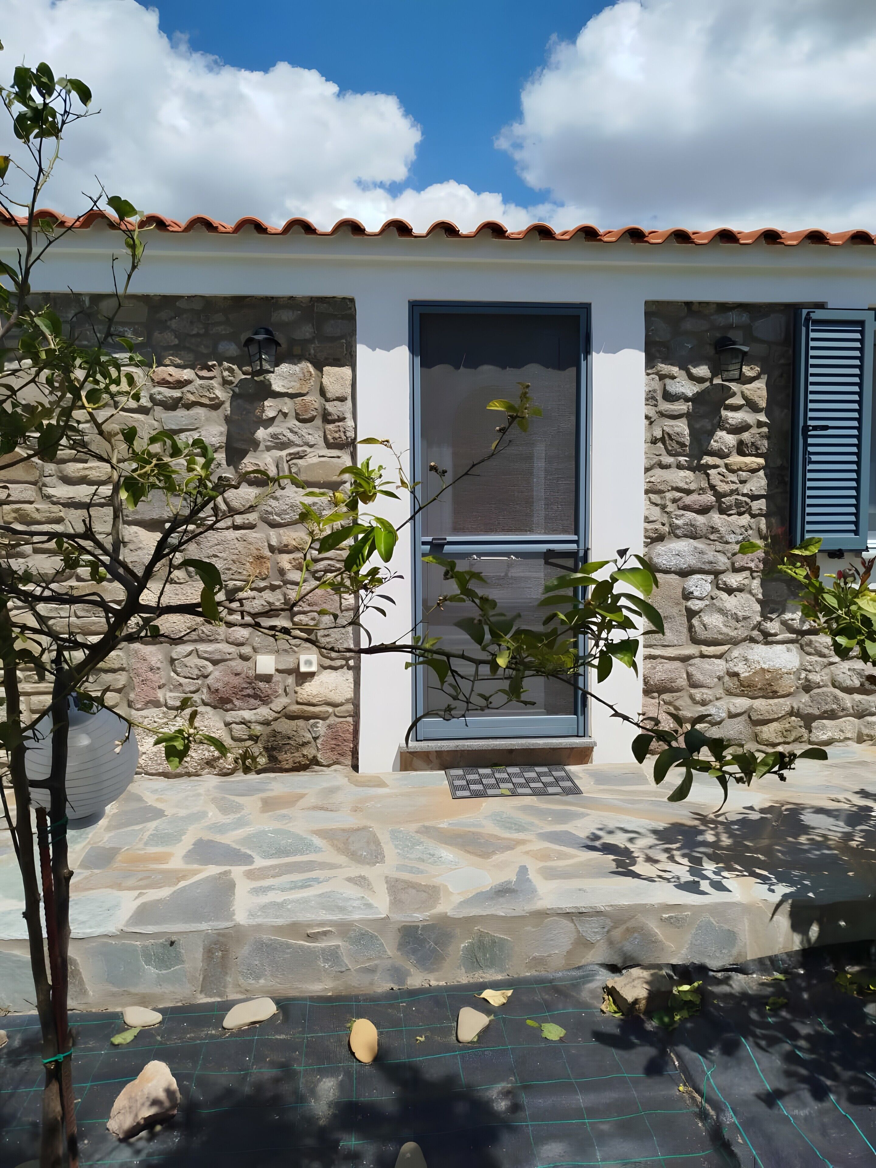 Un edificio con fachada de piedra, tejado de tejas y una puerta con ventanal.