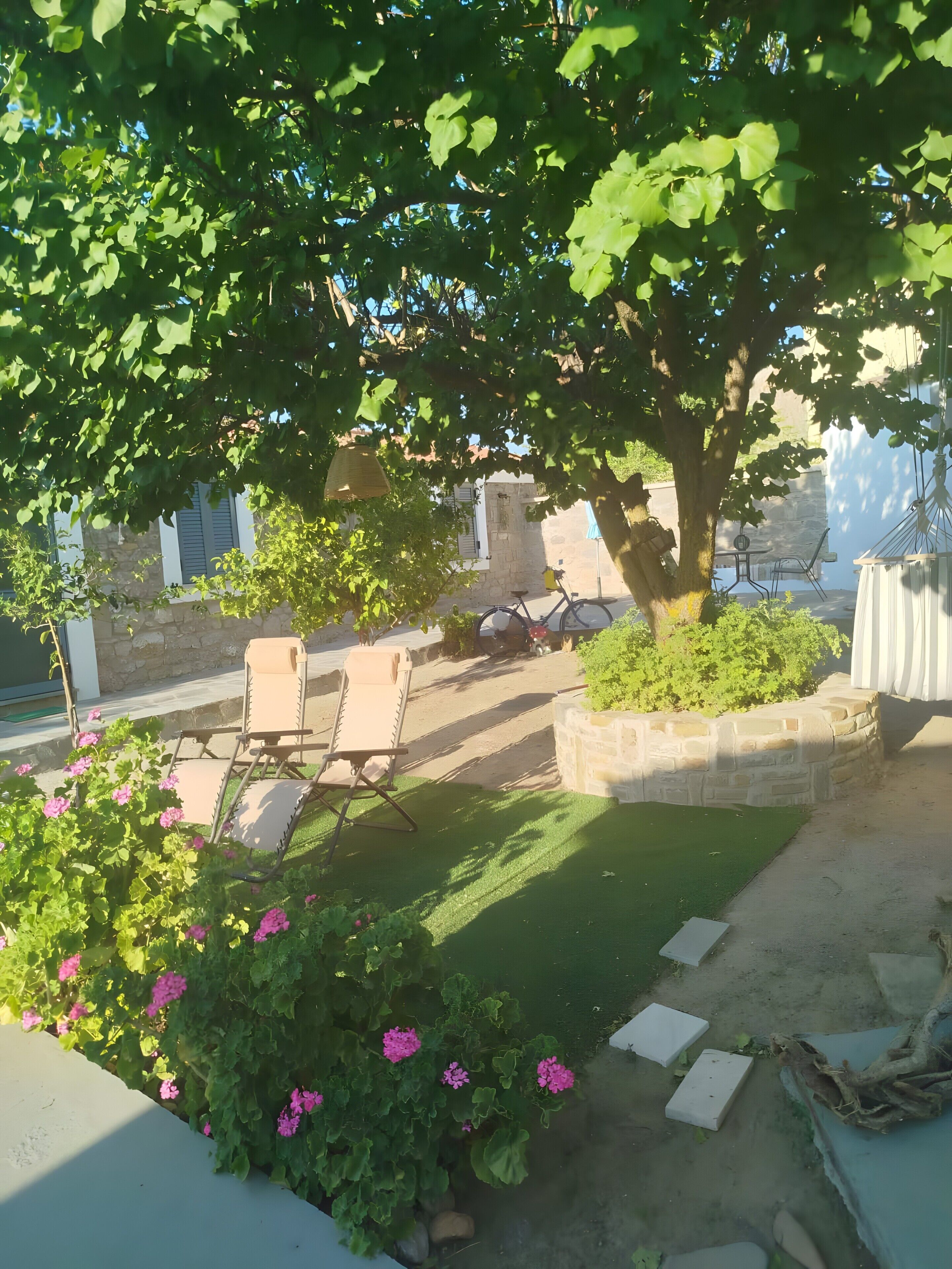 A garden with a tree, a stone wall, and outdoor furniture.