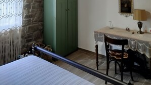 Ett rum med en säng, en grön garderob, ett bord med en lampa och en tavla på väggen.