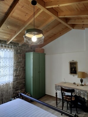 Et værelse med en seng, et grønt klædeskab, et bord med en lampe og et billede på væggen.