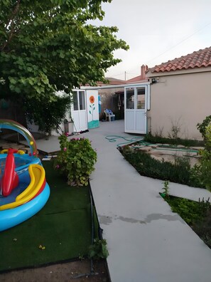Et boligområde udendørs med swimmingpool, have og en overdækket terrasse.