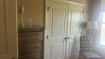 A room with a wardrobe, a chair, and a lamp.