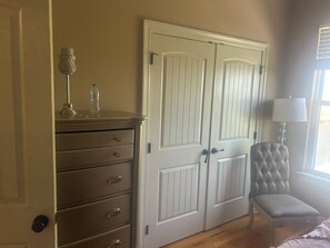 A room with a wardrobe, a chair, and a lamp.