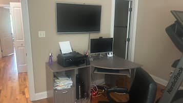 A home office setup with a desk, computer, printer, and a treadmill.