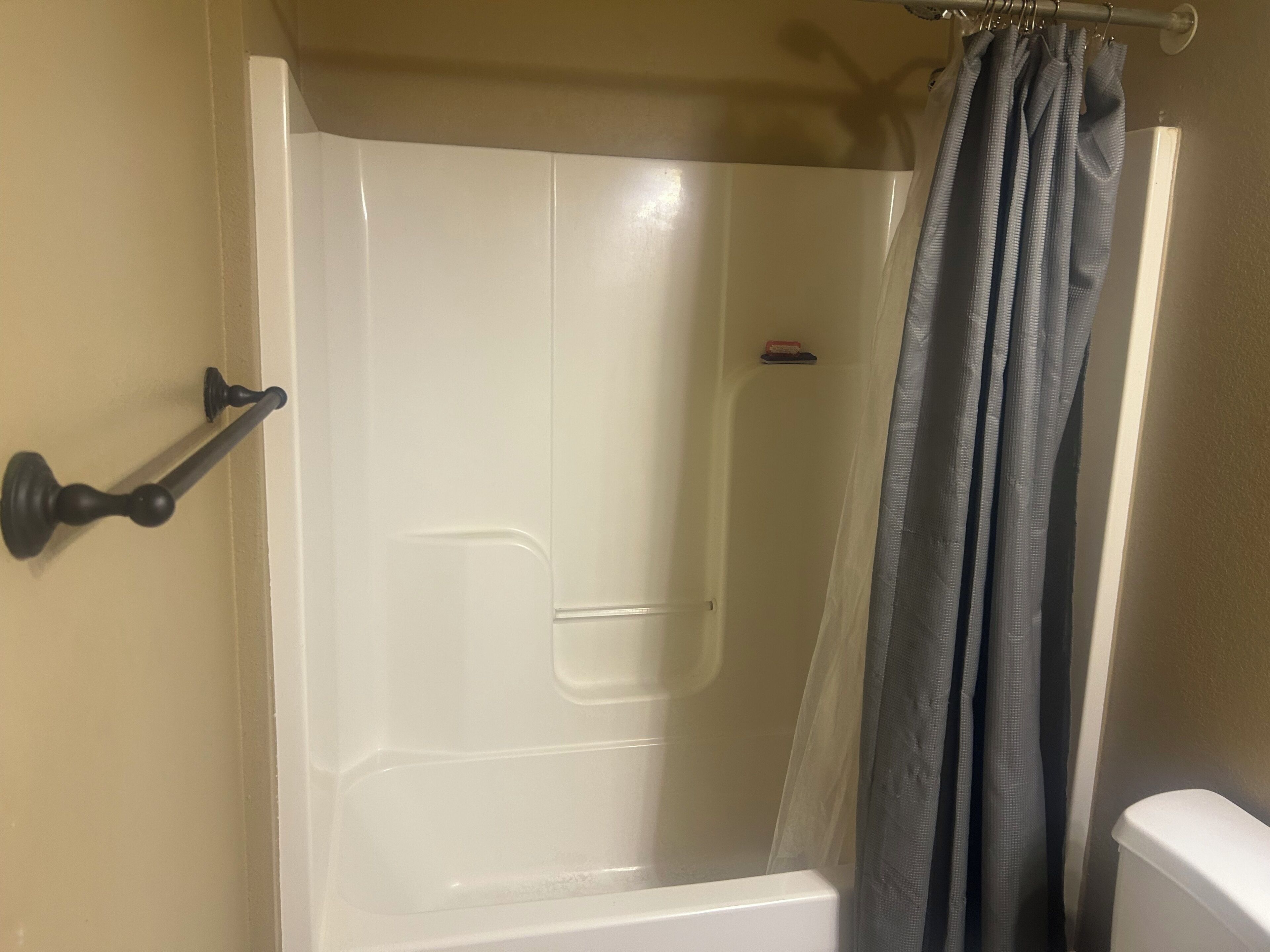 A shower with a white door, a black towel rack, and a shower curtain.