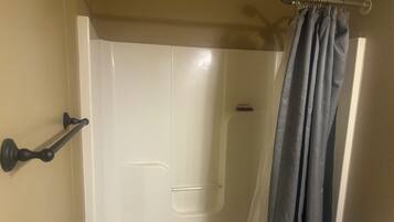 A shower with a white door, a black towel rack, and a shower curtain.