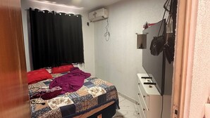 A bedroom with a bed, a desk, a wall-mounted air conditioner, and a curtain. - Cozy apartment (Manaus)