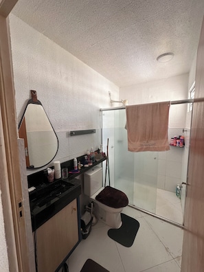 Een badkamer met toilet, douche, spiegel en handdoekhouder.