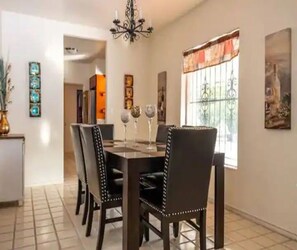 Uma sala de jantar com mesa, cadeiras e um lustre.
