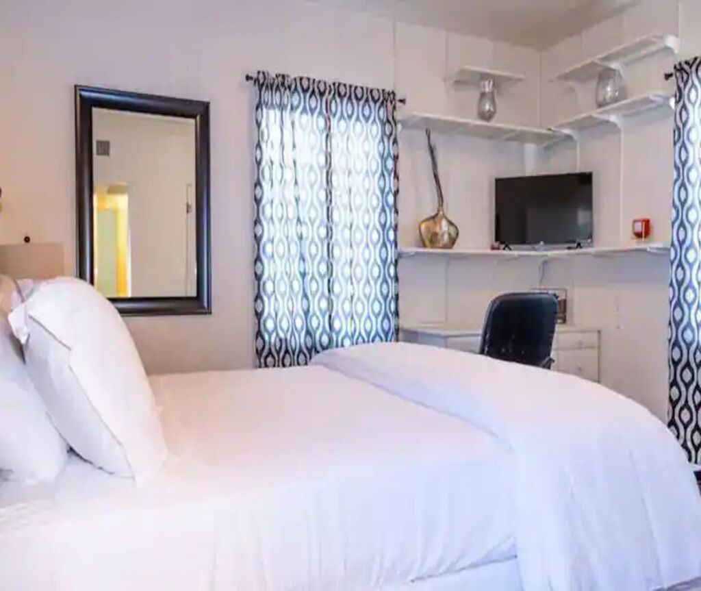 A hotel room with a bed, a television, a desk, and a chair.