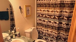 Une salle de bain équipée d’un lavabo, de toilettes et d’un rideau de douche à motifs animaliers.