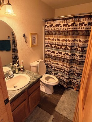 Un baño con lavamanos, inodoro y cortina de ducha con estampados de animales.