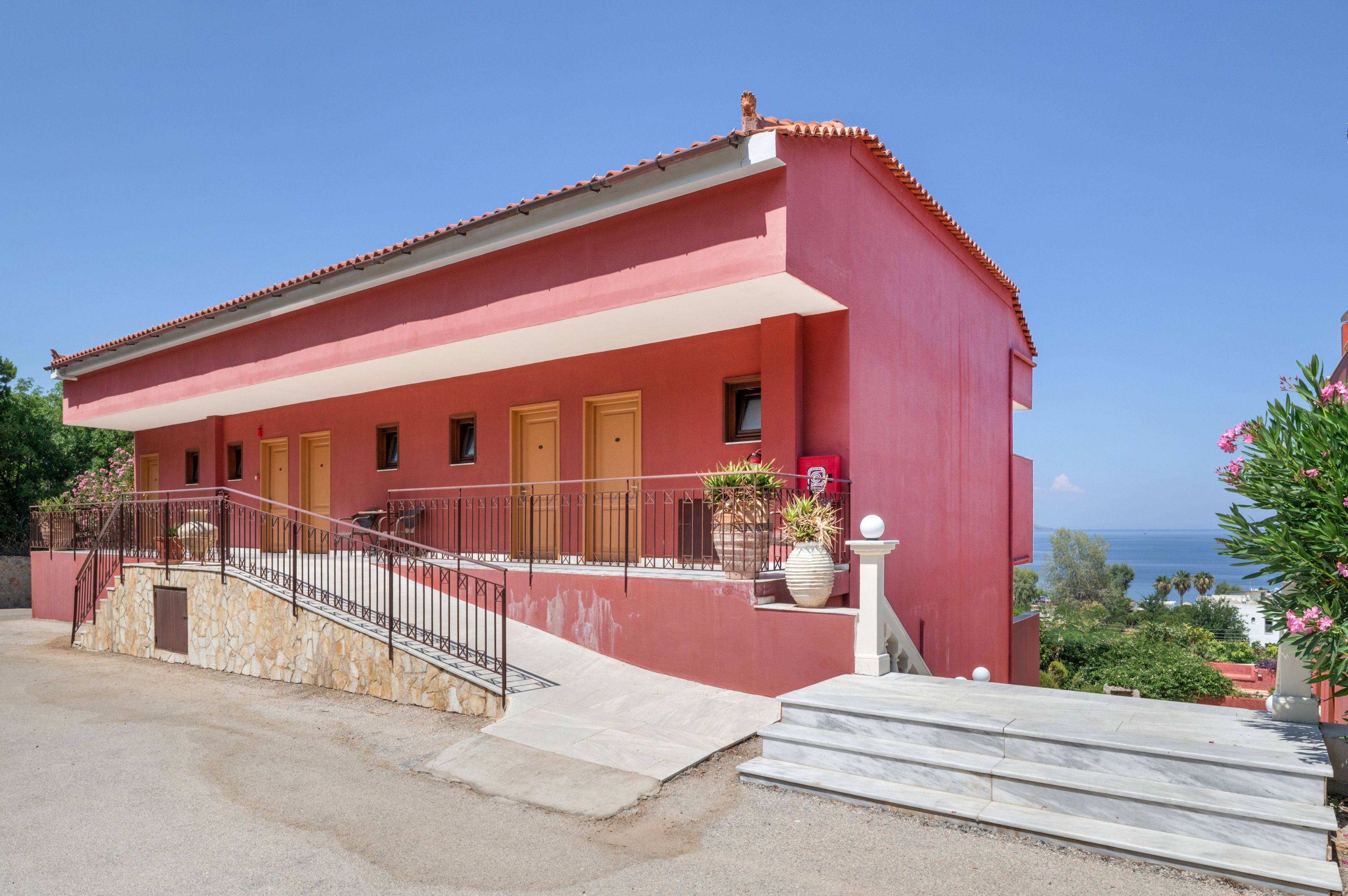 Un bâtiment rouge avec un toit en tuiles, un escalier en pierre et une vue sur la mer.