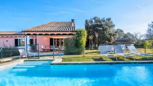 A residential property with a swimming pool, outdoor seating, and a garden.