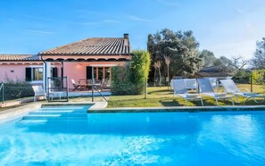 A residential property with a swimming pool, outdoor seating, and a garden.