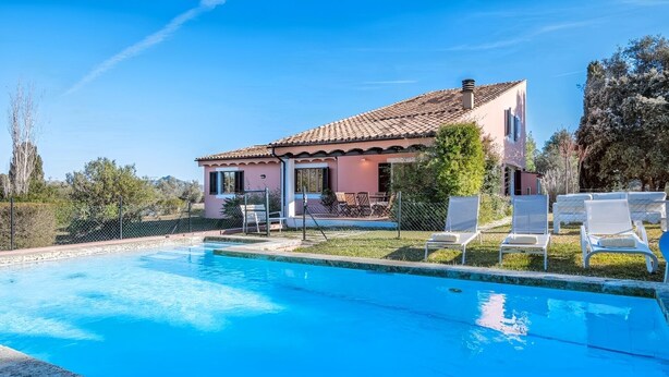 A house with a swimming pool, outdoor seating, and a clear sky.