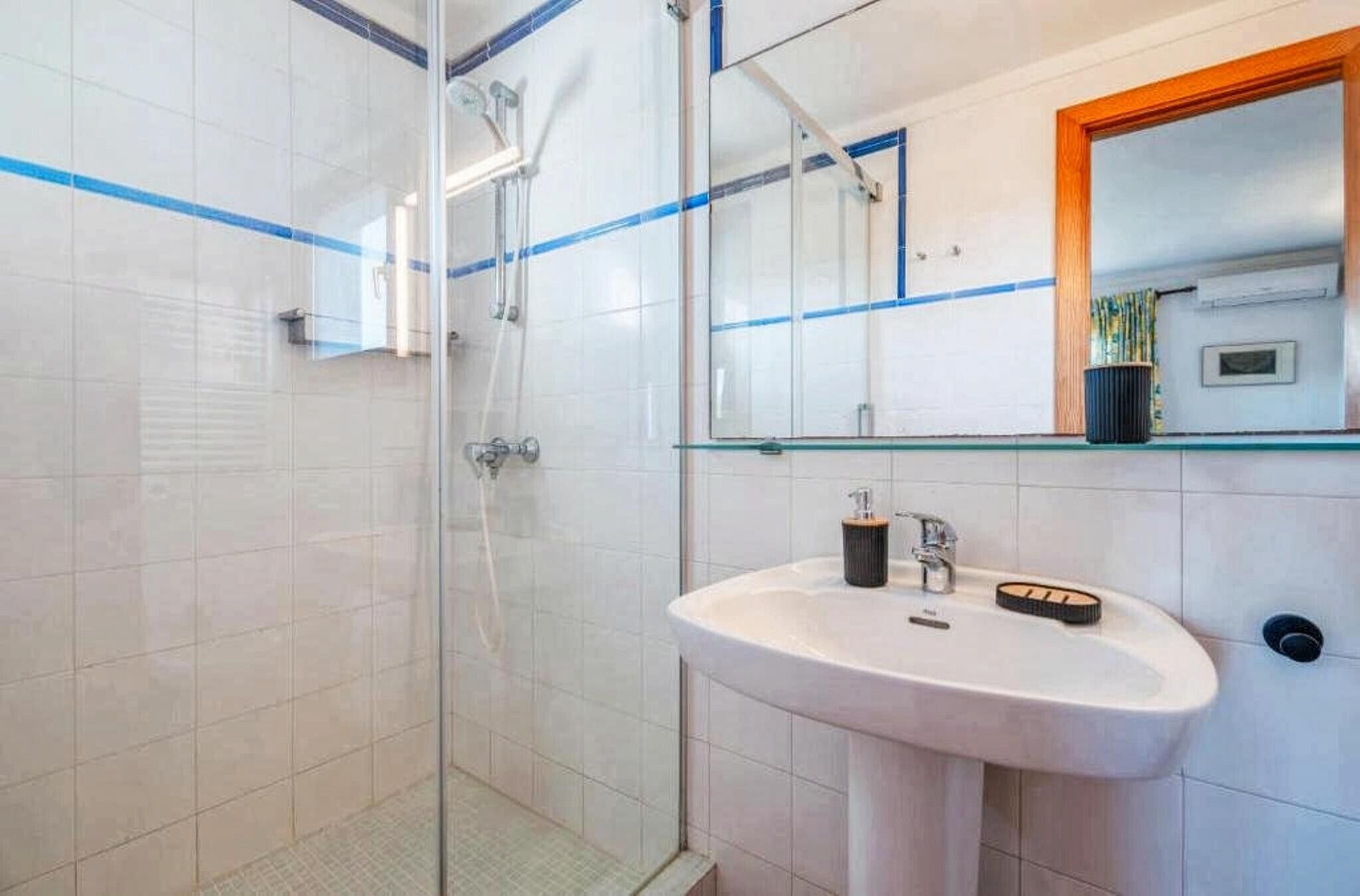 A bathroom with a glass-enclosed shower, a white sink, and a mirror above the sink.