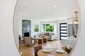 A modern living room with a sofa, chairs, and a dining table set for two. - Newly Renovated Luxury Home near Stanford & Techs (East Palo Alto)