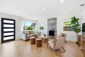 A modern living room with a sofa, armchairs, a coffee table, and a fireplace. - Newly Renovated Luxury Home near Stanford & Techs (East Palo Alto)