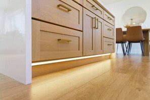 A modern kitchen with wooden cabinetry and integrated under-cabinet lighting. - Newly Renovated Luxury Home near Stanford & Techs (East Palo Alto)