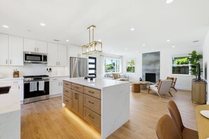 A modern kitchen with white cabinetry, stainless steel appliances, and a central island. - Newly Renovated Luxury Home near Stanford & Techs (East Palo Alto)