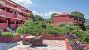 A red building with balconies, a checkered patio, and outdoor furniture. - Classic Double Room at Hotel Aristotelis with Sea View and Balcony (Ancient Epidavros)