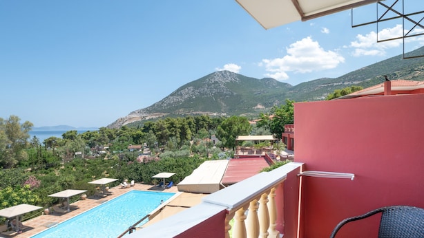 A balcony with a pool, a table, and a view of the sea and mountains. - Classic Double Room at Hotel Aristotelis with Sea View and Balcony (Ancient Epidavros)