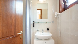 A bathroom with a wooden door, a glass shower enclosure, a white sink with a mirror above it, and a toilet. - Classic Double Room at Hotel Aristotelis with Sea View and Balcony (Ancient Epidavros)