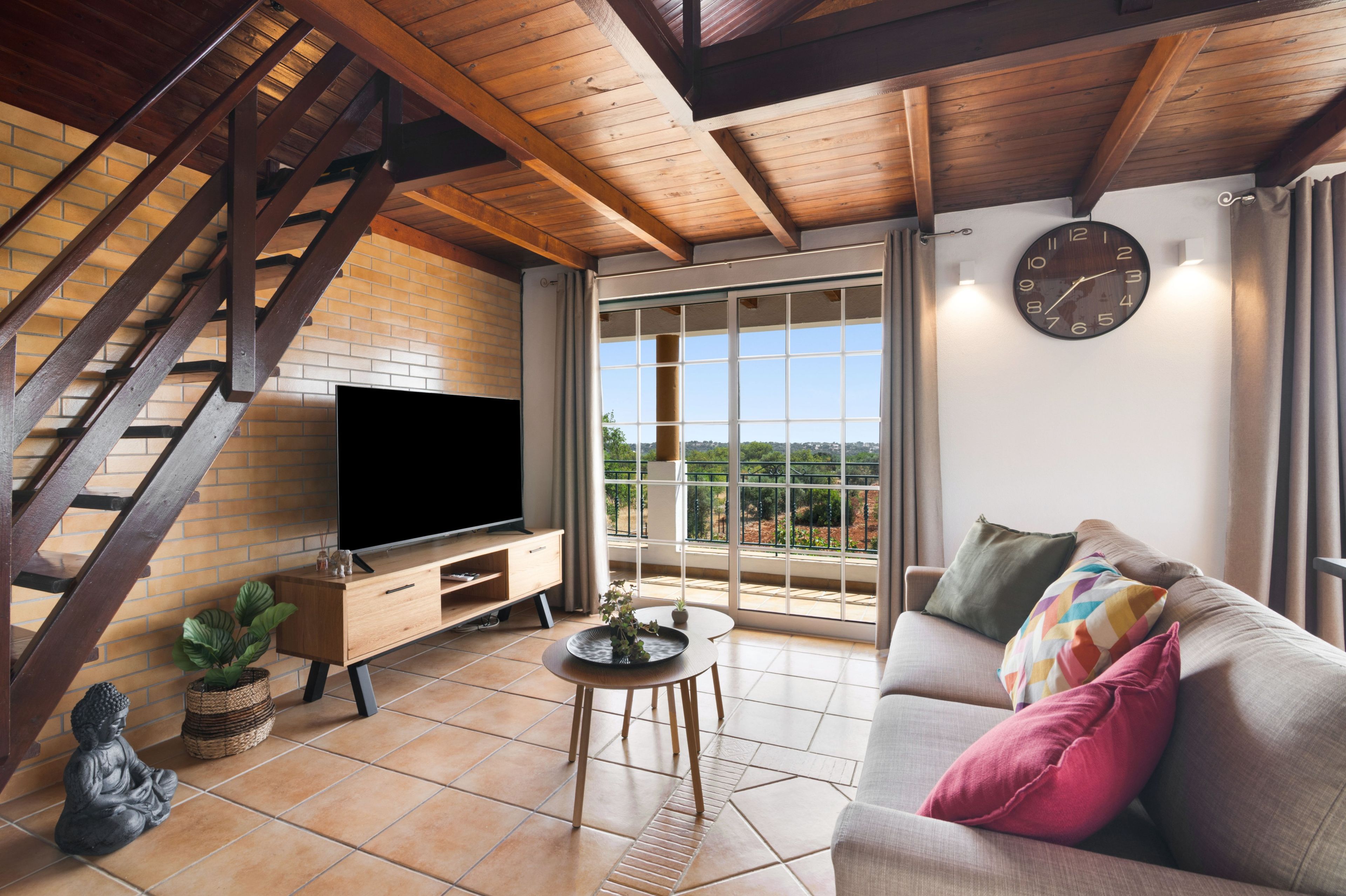 Ein Wohnzimmer mit Fernseher, Sofa und einer Treppe.