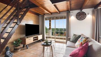 Ein Wohnzimmer mit Fernseher, Sofa und einer Treppe.