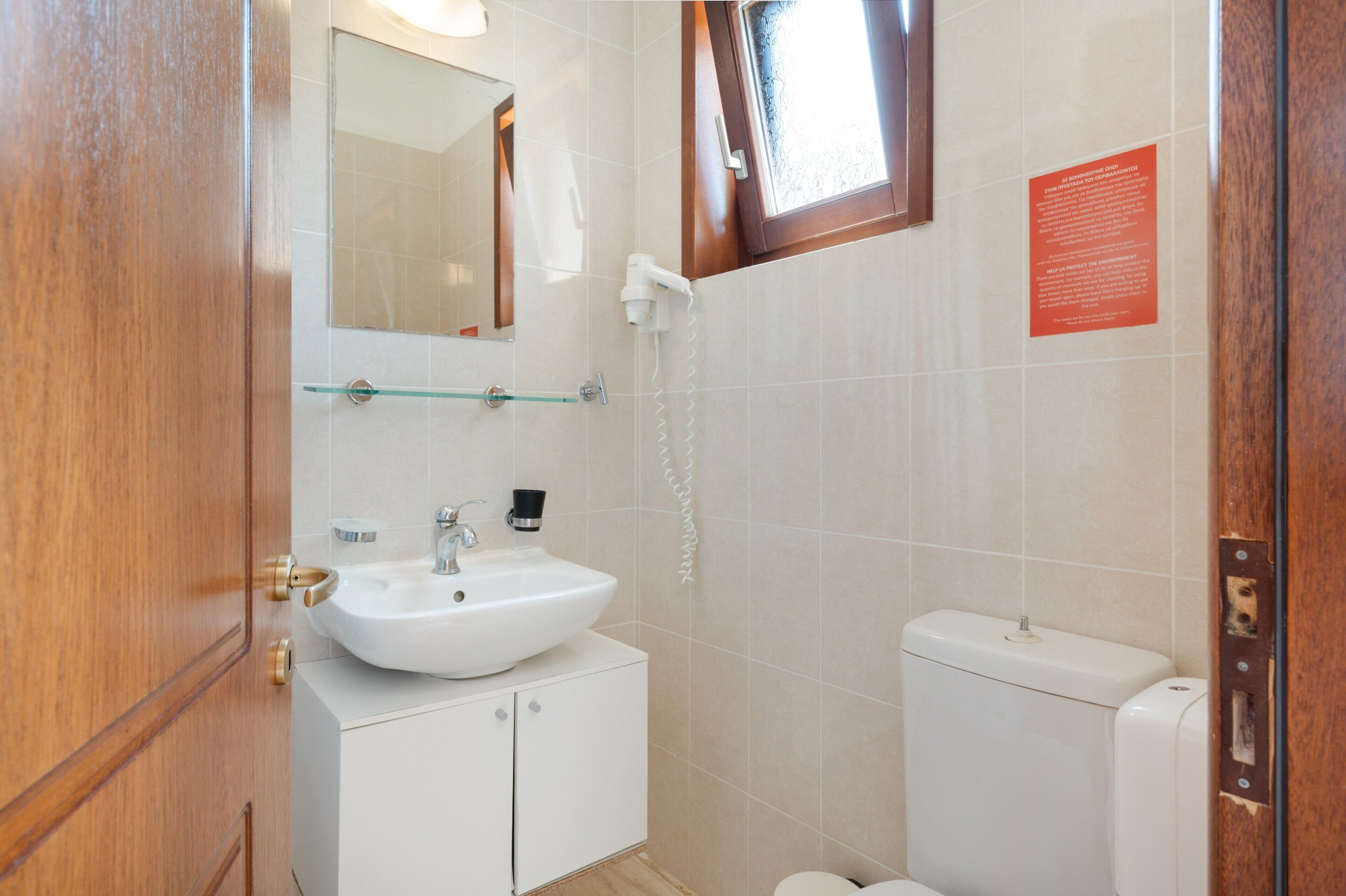 Une salle de bain avec un lavabo blanc, un miroir, une étagère en verre, des toilettes et une douche.