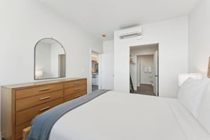 Un dormitorio con cama, cómoda, espejo y aire acondicionado.
