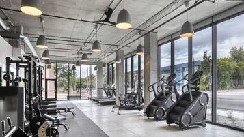 A gym with exercise equipment, large windows, and pendant lighting.