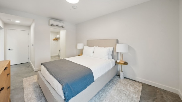 A modern bedroom with a bed, bedside tables, and a door leading to a bathroom. - One Bedroom with Private Balcony City View | Downtown Location (Salt Lake City)