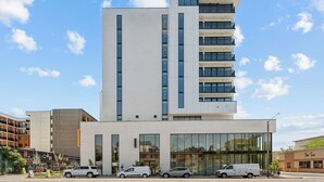A modern multi-story building with a flat facade, large windows, and a ground-level entrance. - One Bedroom with Private Balcony City View | Downtown Location (Salt Lake City)