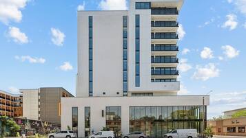 A modern multi-story building with a flat facade, large windows, and a ground-level entrance.