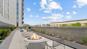 A rooftop patio with a fire pit, seating, and a view of the cityscape. - Modern One bedroom Unit w/ Private Laundry access in Placemakr Salt Lake City (Salt Lake City)