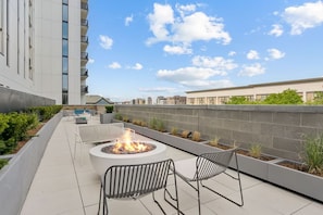 Una terraza en la azotea con un hogar para fuego, asientos y vistas de la ciudad.