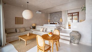 Una sala moderna con sofá, mesa de centro, mesa de comedor y sillas. Hay un jarrón grande y un frutero sobre la mesa.