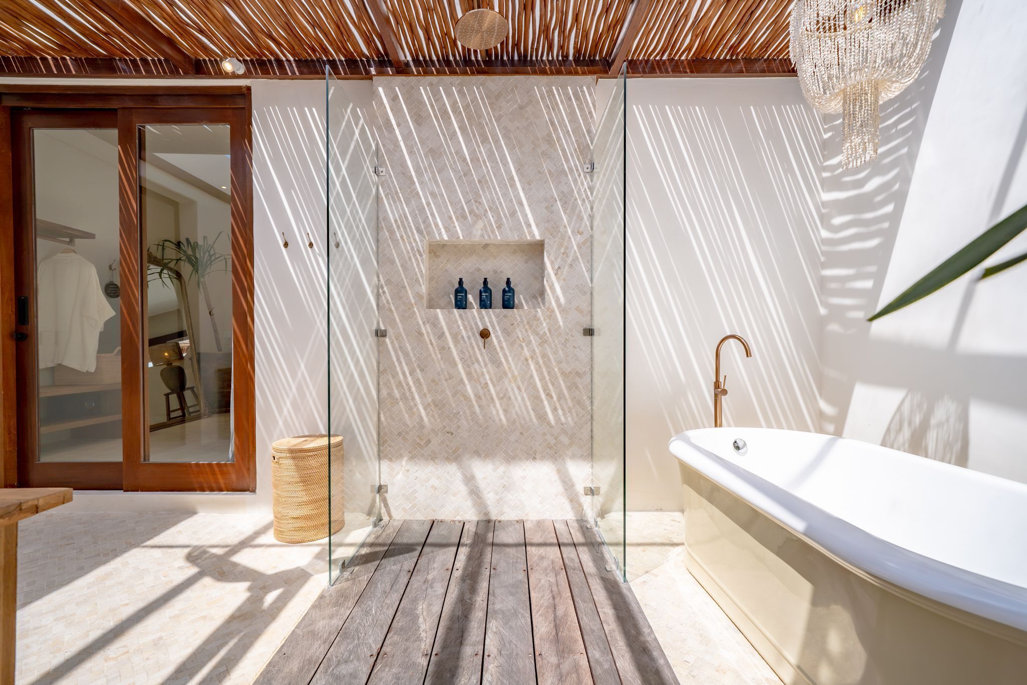 Un baño moderno con ducha envuelta en vidrio, suelo de madera y una bañera blanca.