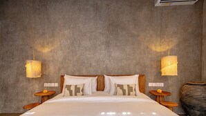 Un dormitorio con una cama grande, dos mesitas de noche, un aire acondicionado de pared y una pared con textura.