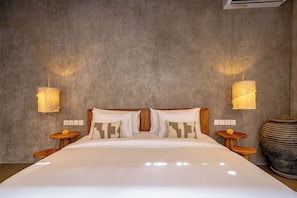 Un dormitorio con una cama grande, dos mesitas de noche, un aire acondicionado de pared y una pared con textura.