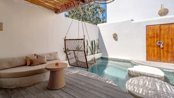 Un área junto a la piscina con una silla colgante, un sofá y una puerta de madera.