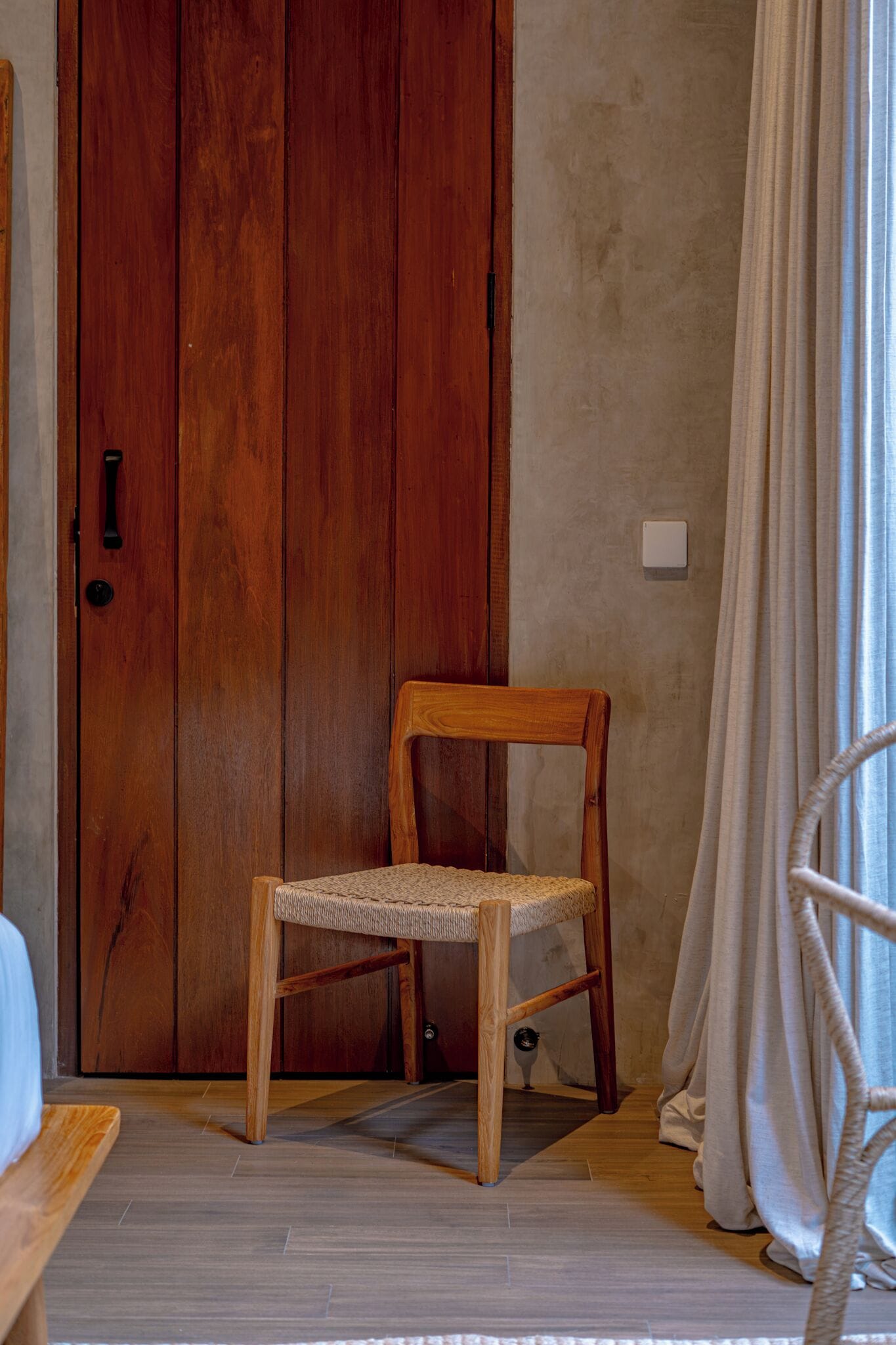 Una silla de madera con asiento tejido frente a una puerta de madera.
