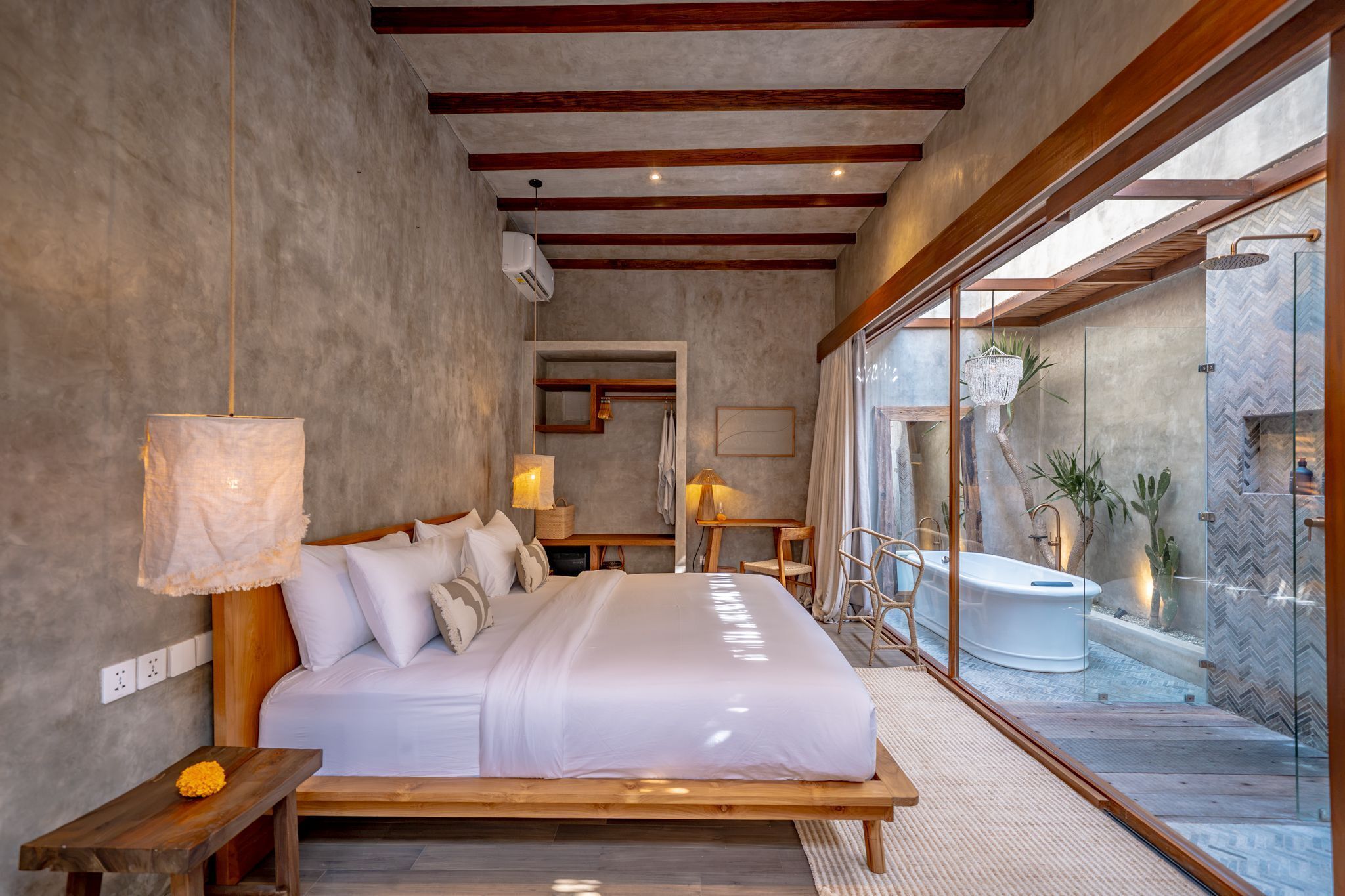 A modern bedroom with a large bed, bedside lamps, a view of an outdoor jacuzzi, and a wooden ceiling.