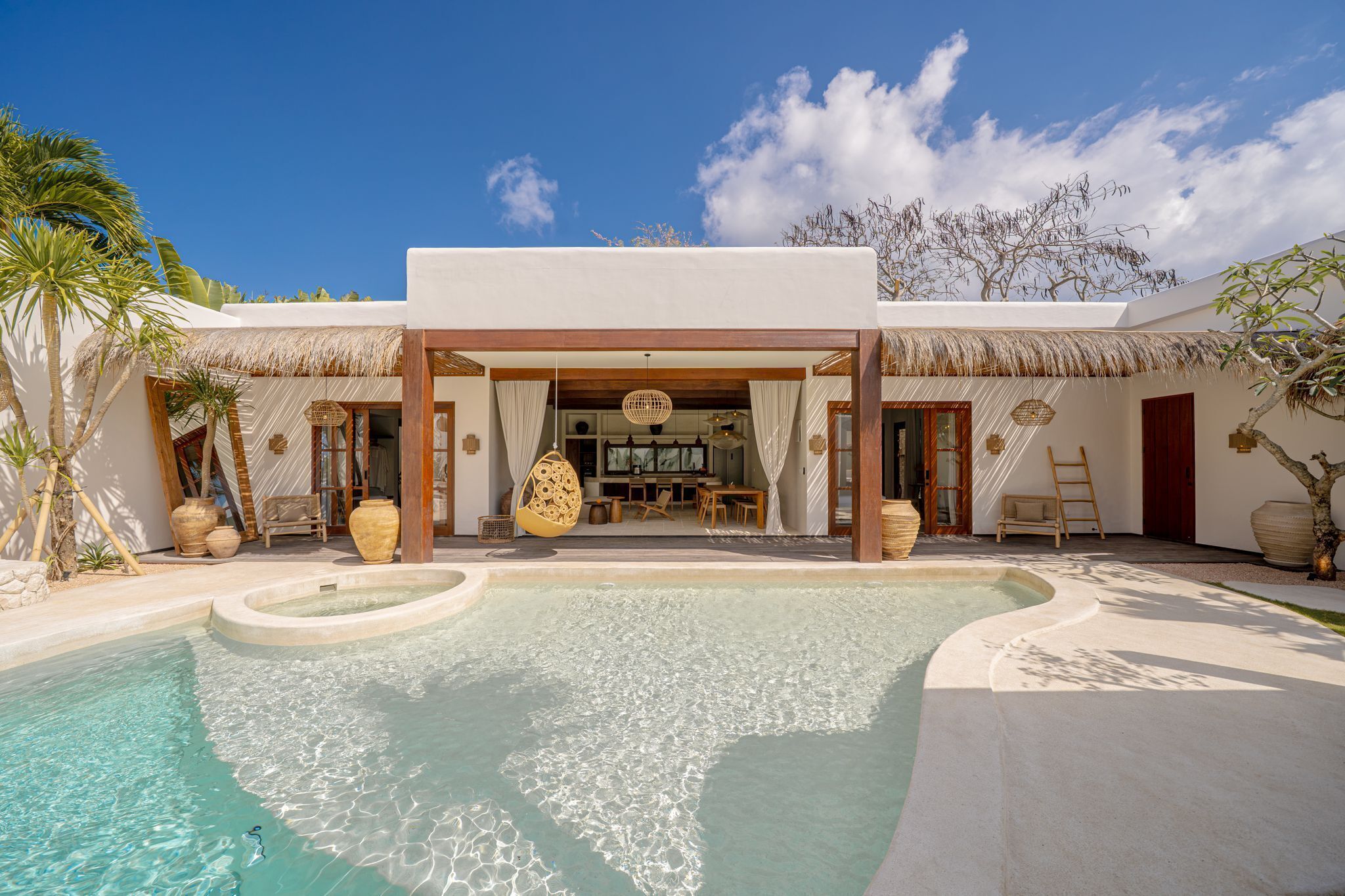 Ein Resort mit Pool, Sitzgelegenheiten im Freien und einem Gebäude mit einem Reetdach.