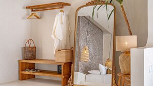 Un baño con un espejo grande y ornamentado, un banco de madera, una toalla colgada, una cesta tejida y una planta.