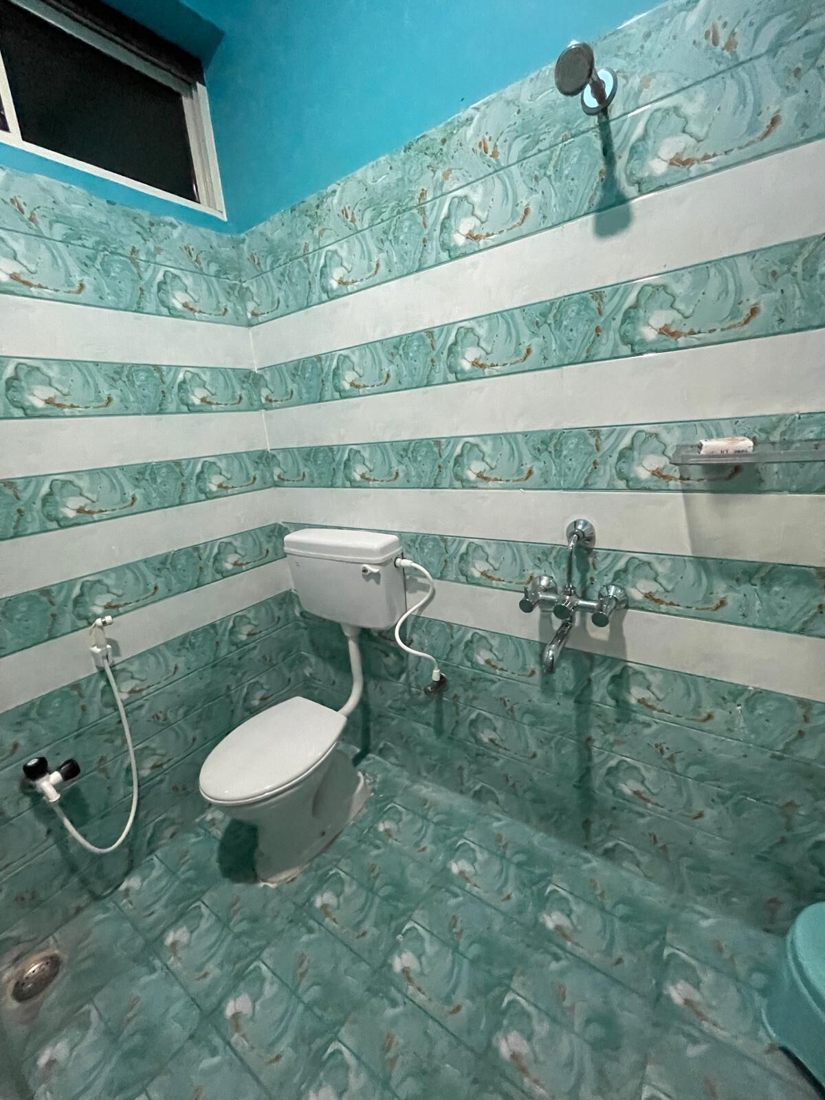 A bathroom with a toilet, bidet, and shower. The walls have a marble-like pattern.
